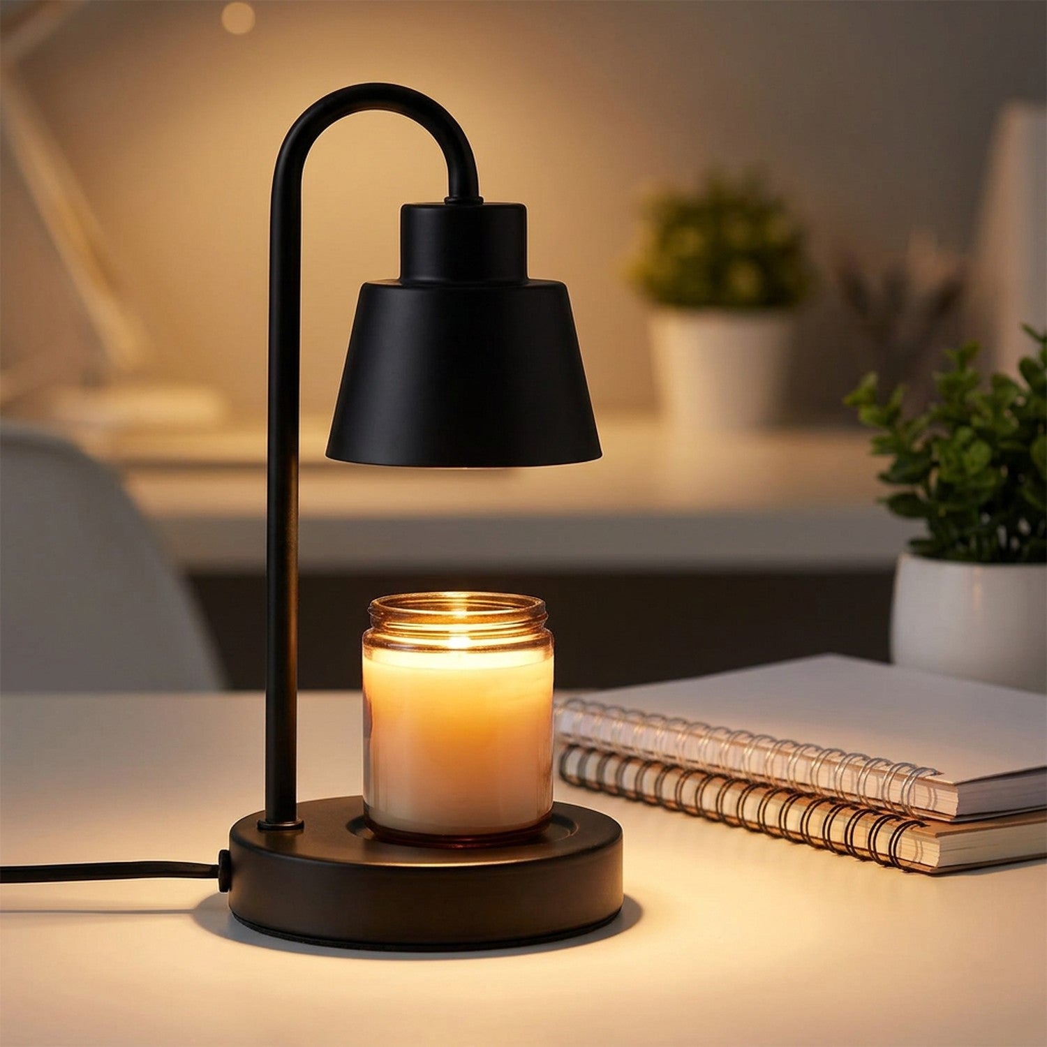 Lampe chauffe-bougie noire sur un bureau avec bougie parfumée près de carnets