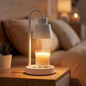 Lampe chauffe-bougie blanche allumée avec bougie parfumée sur une table de chevet en bois