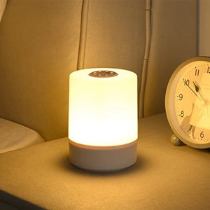 Lampe de chevet allumée avec lumière chaude posée sur une table de nuit près d'un réveil