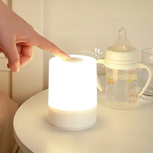 Lampe de chevet tactile allumée à côté d'un biberon sur une table