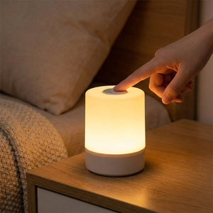 Main effleurant le bouton tactile de la lampe de chevet allumée la nuit