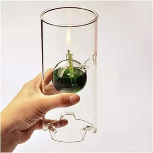 Main tenant la lampe à huile ouragan en verre avec liquide vert et flamme allumée