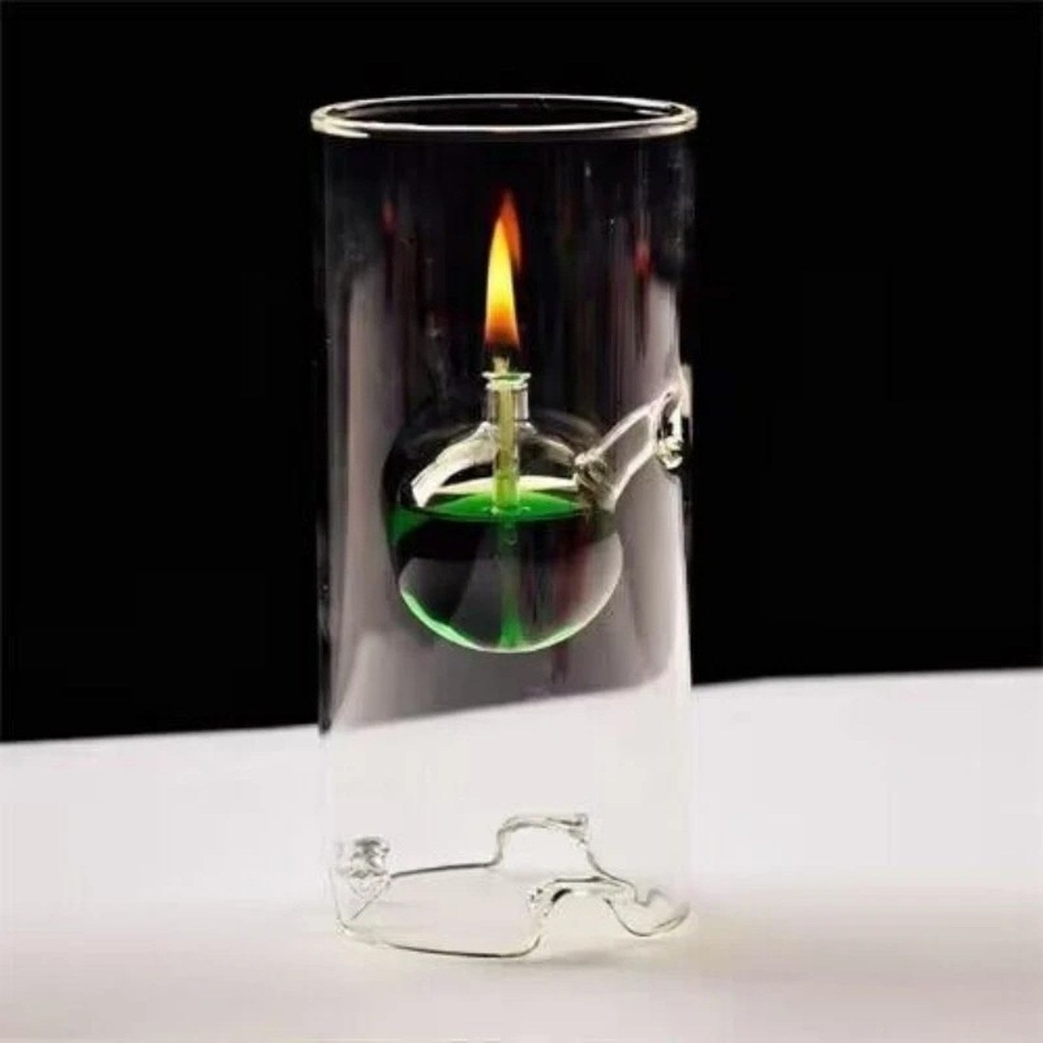 Lampe à huile ouragan en verre transparent avec boule de liquide vert et flamme sur fond sombre