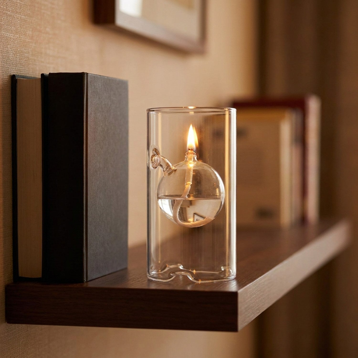 Lampe à huile ouragan transparente posée sur une étagère près de livres