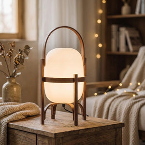 Lampe lanterne en bois noyer foncé et globe de verre opale allumée sur une table