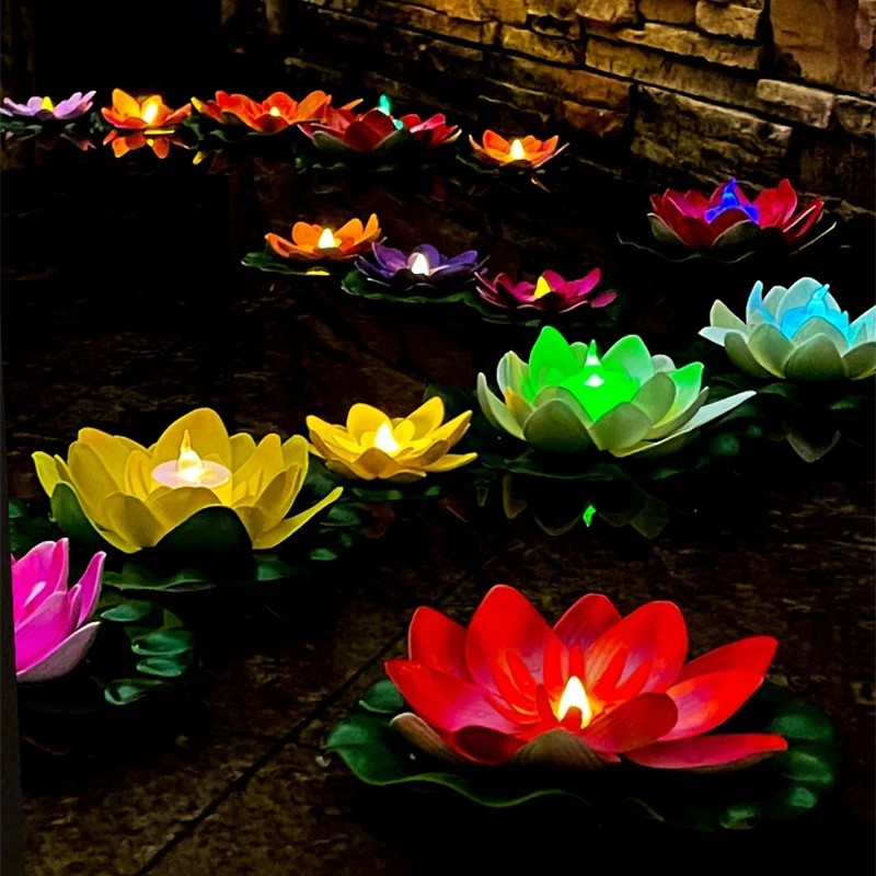 Plusieurs lampes lotus flottantes LED allumees sur un bassin la nuit