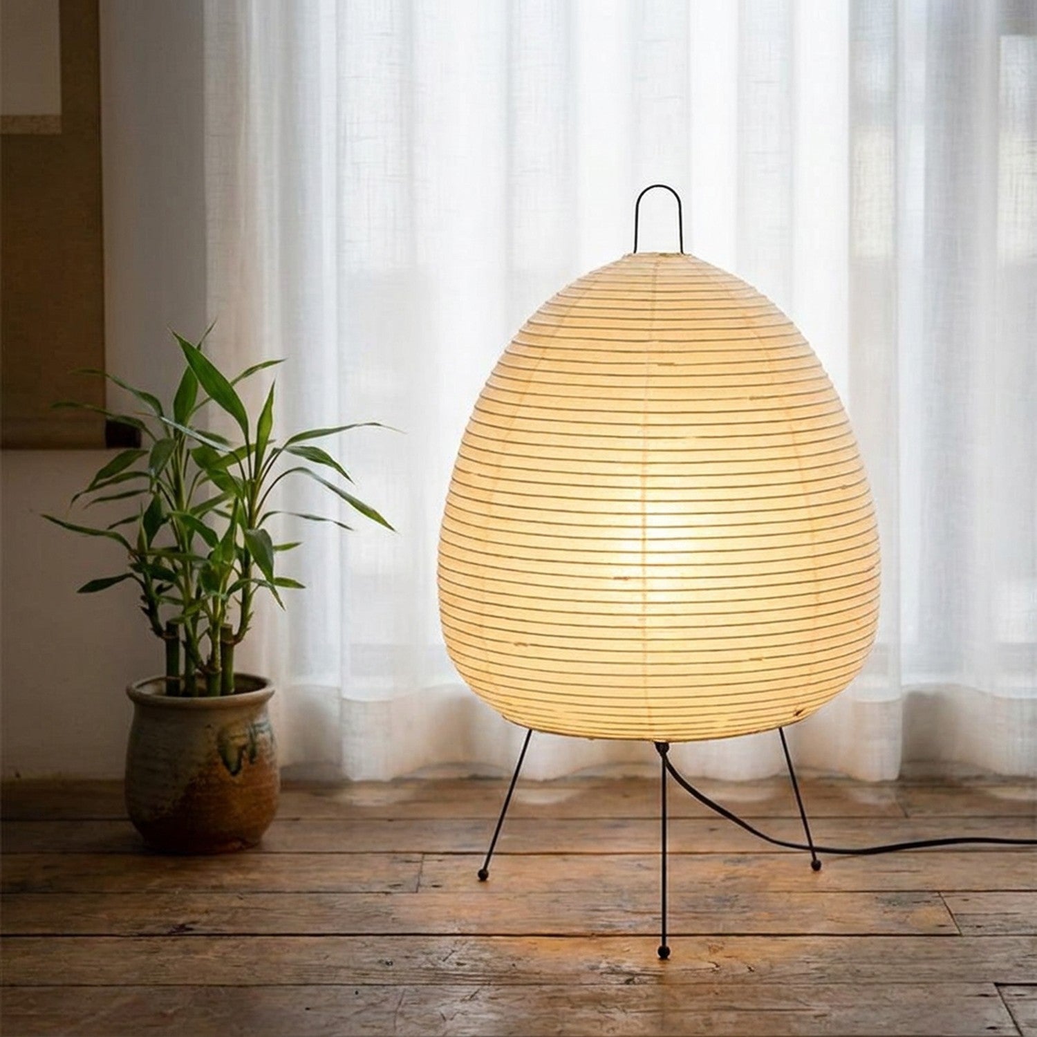 Lampe papier de riz dans un coin lecture avec plante bambou et rideau voilage blanc
