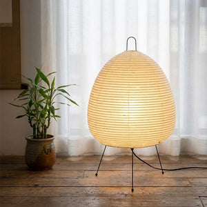 Lampe papier de riz dans un coin lecture avec plante bambou et rideau voilage blanc