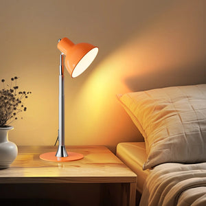 Lampe LED orange en version bureau posée sur une table de chevet