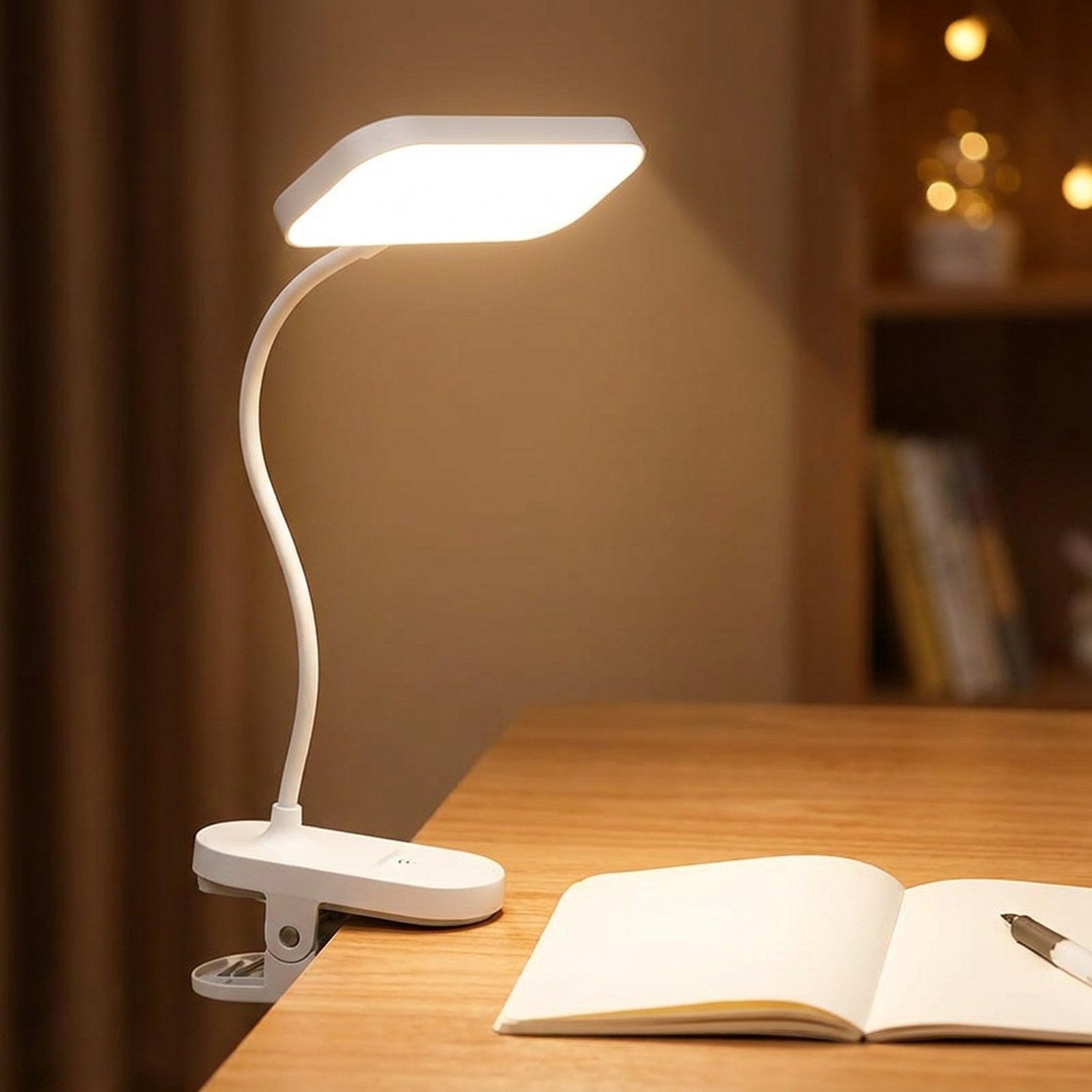 Lampe à pince LED allumée sur un bureau près d un carnet ouvert pour lire le soir