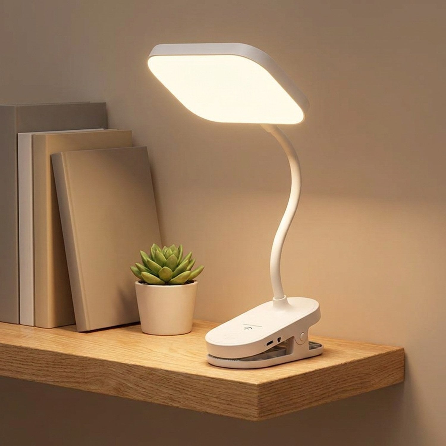 Lampe à pince LED col de cygne posée sur une étagère avec livres et plante