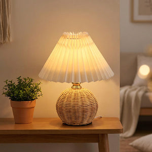 Lampe en rotin et abat-jour plissé posée sur une console dans un salon chaleureux