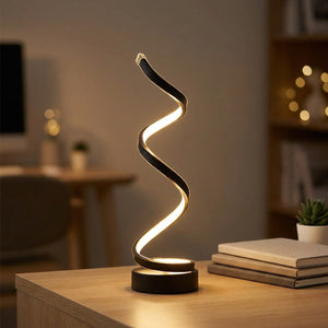 Lampe spirale LED allumée sur un bureau en bois clair avec des livres