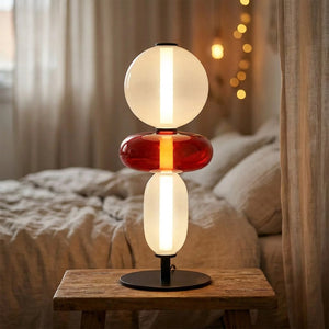 Lampe de table LED 3 globes verre teinté design nordique allumée sur table de chevet