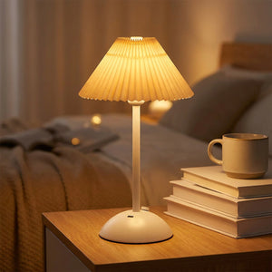 Lampe de table sans fil avec abat-jour plissé beige crème allumée sur une table de nuit
