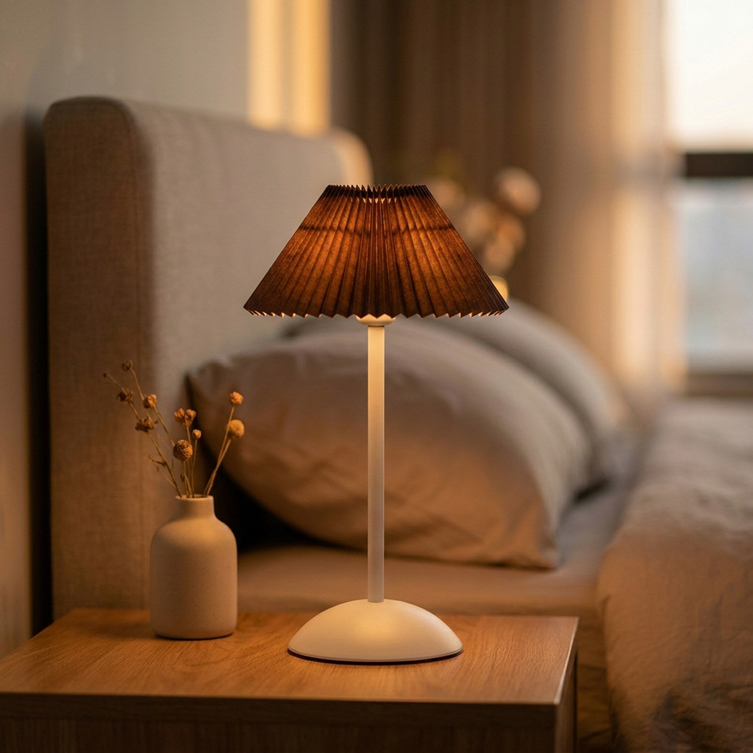 Lampe de table sans fil avec abat-jour plissé marron allumée sur une table de nuit