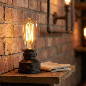 Lampe tuyau industrielle allumée sur une étagère en bois contre un mur de brique