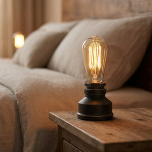 Lampe tuyau industrielle allumée près d'un canapé lin beige le soir
