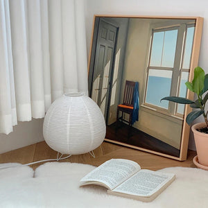 Lampe wabi-sabi allumée près d'un rideau blanc et d'un tableau encadré