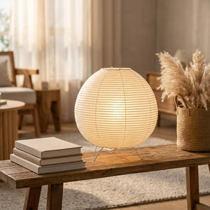 Lampe wabi-sabi allumée sur un meuble bas en bois avec livres et pampas dans un salon nordique