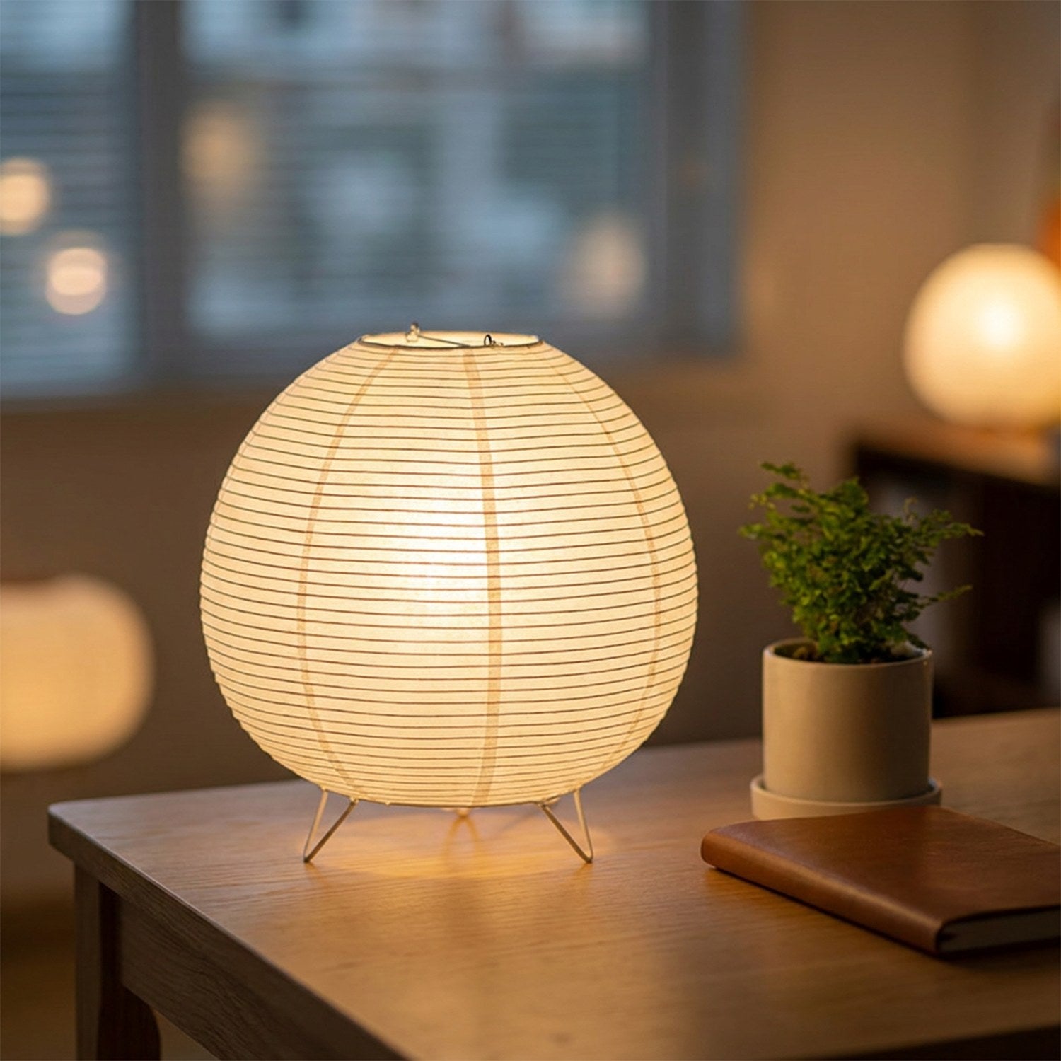 Lampe wabi-sabi allumée sur un bureau en bois clair avec une plante verte