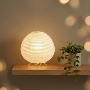 Lampe wabi-sabi allumée sur une étagère murale flottante avec une plante retombante