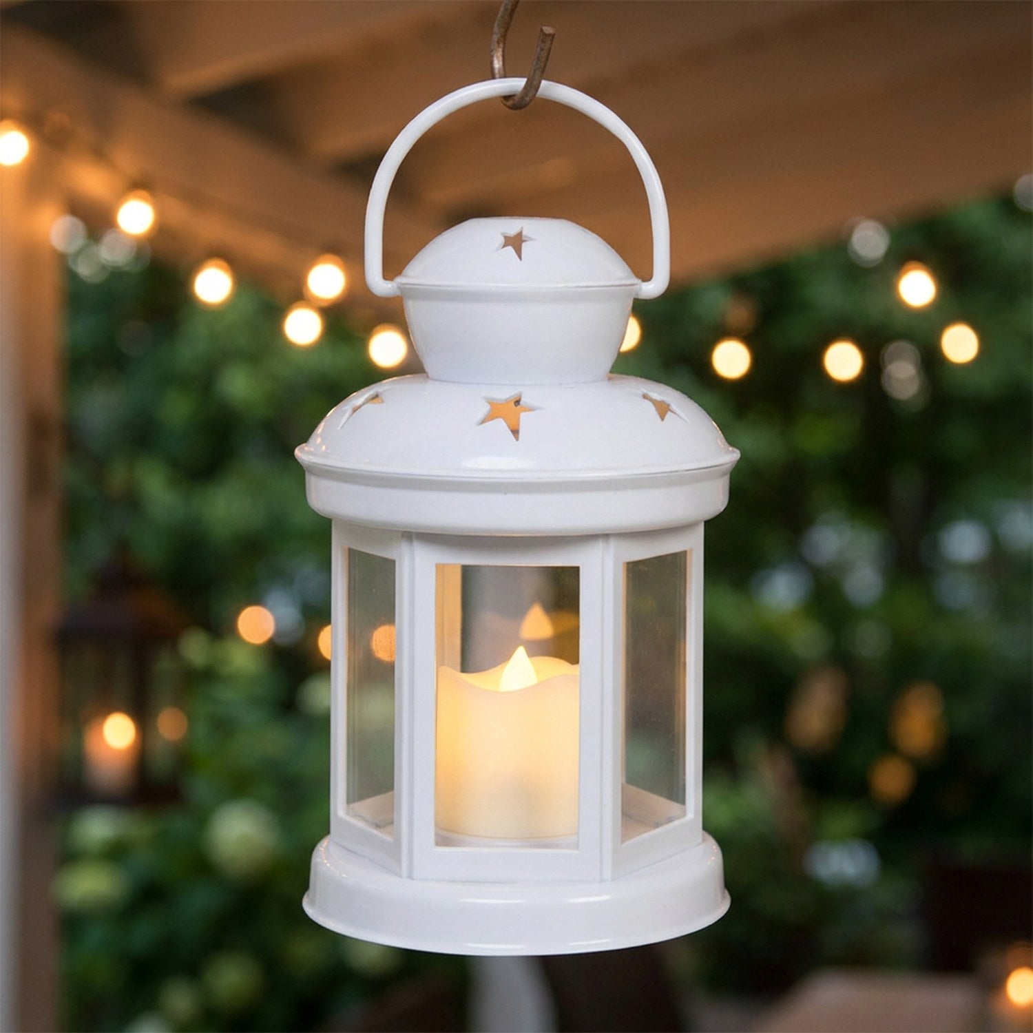 Lanterne étoile blanche suspendue à un crochet sur une terrasse cosy le soir