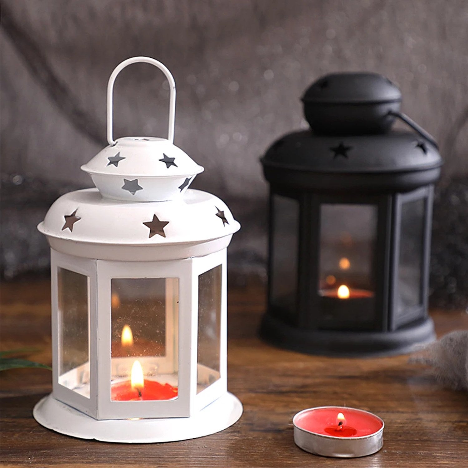 Lanternes étoiles blanche et noire allumées avec bougies sur une table en bois