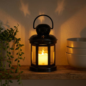 Lanterne étoile noire allumée sur une étagère bohème avec une plante