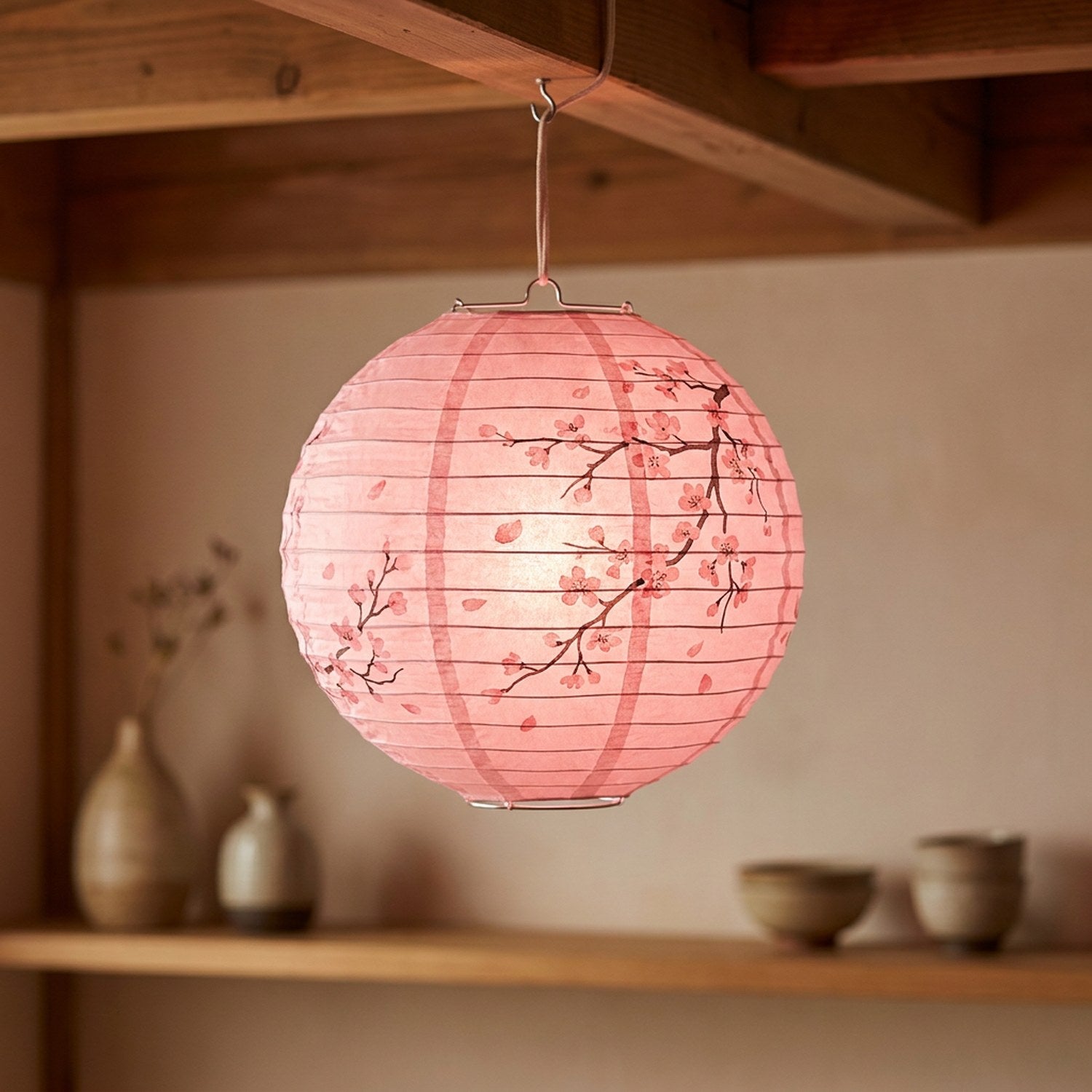Lanterne japonaise en papier rose suspendue aux motifs fleurs de pêcher dans un espace zen