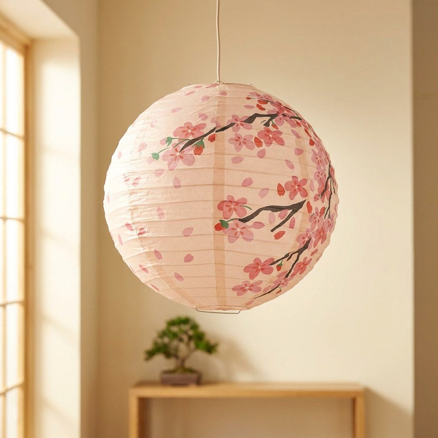 Lanterne japonaise en papier motif fleurs de cerisier rose suspendue dans un intérieur zen