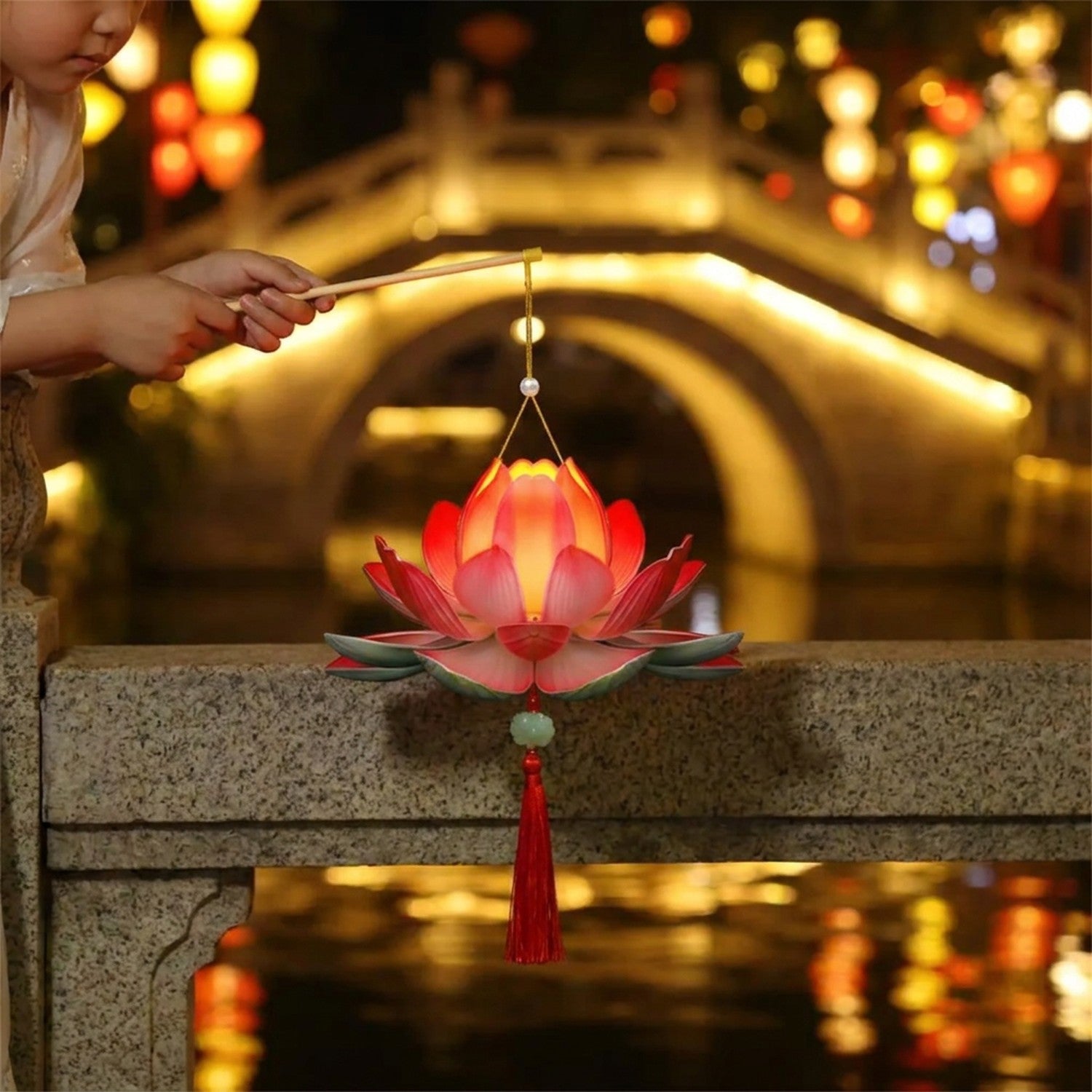 Enfant tenant une lanterne lotus LED allumée sur un pont la nuit pendant une fête