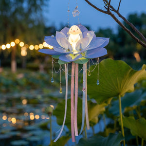 Lanterne lotus bleue suspendue à une branche au bord d'un étang au crépuscule