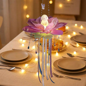 Lanterne lotus violette suspendue au-dessus d'une table de fête décorée de guirlandes lumineuses