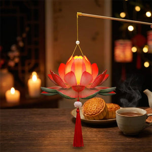 Lanterne lotus LED allumée posée près de mooncakes et d'une tasse de thé