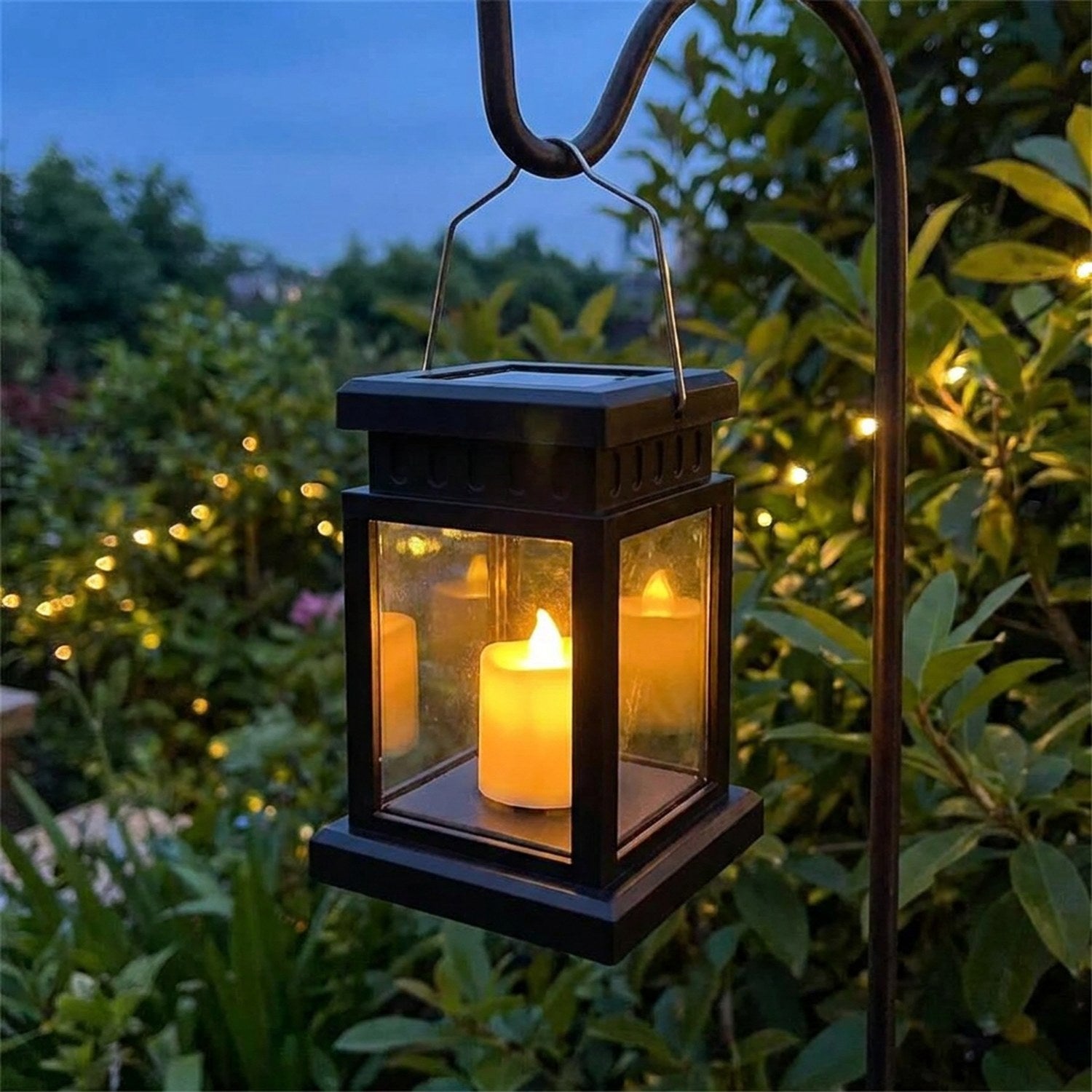 Lanterne solaire d extérieur noire allumée suspendue dans un jardin la nuit