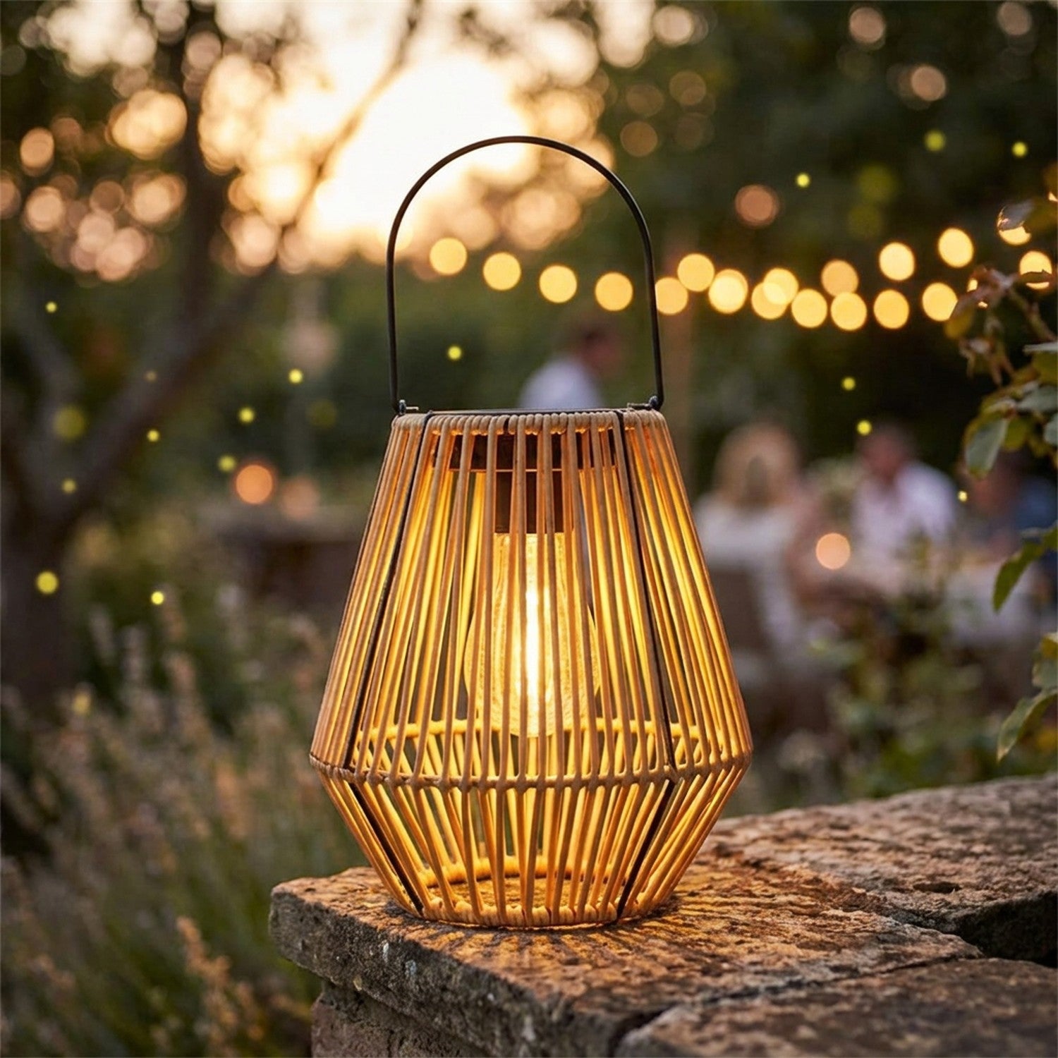 Lanterne solaire géométrique style rotin posée sur un muret de jardin au coucher du soleil