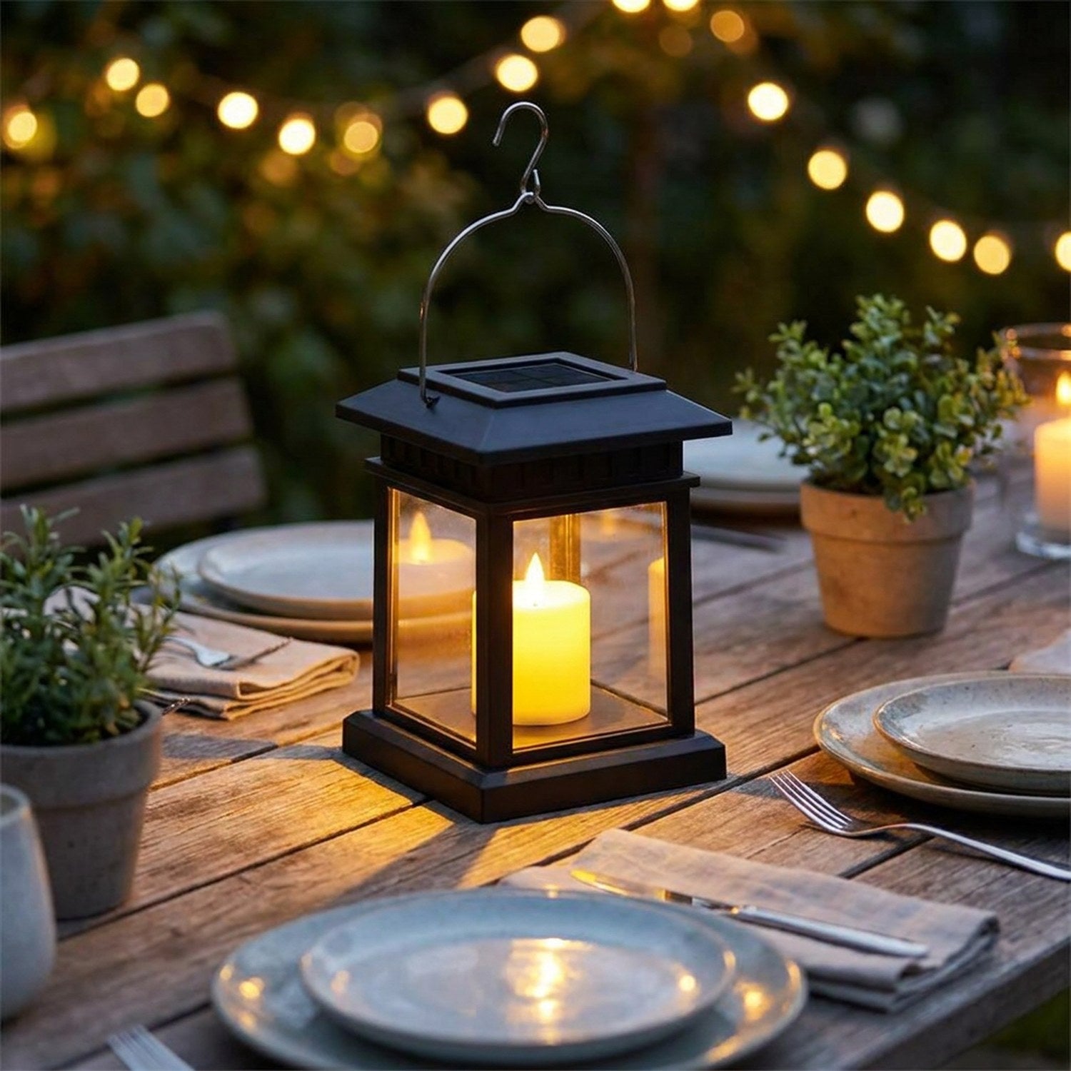 Lanterne solaire noire allumée sur une table de jardin dressée le soir
