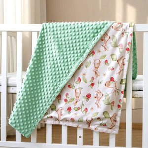 Couverture bébé à pois en relief drapée sur un lit à barreaux dans une chambre lumineuse