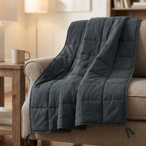 Couverture lestée grise matelassée drapée sur un fauteuil cocooning