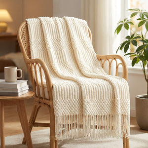 Plaid tricoté crème drapé sur un fauteuil en rotin près d une fenêtre