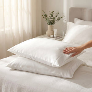 Main effleurant une taie d'oreiller satin blanche dans une chambre lumineuse
