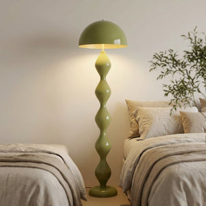 Lampadaire champignon vert olive allumé dans une chambre cosy au linge de lit naturel