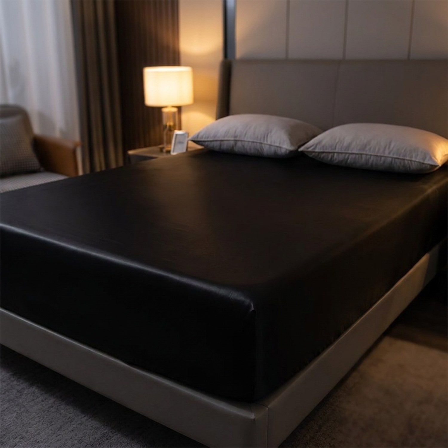 Drap-housse satin noir élastique sur un lit dans une chambre feutrée