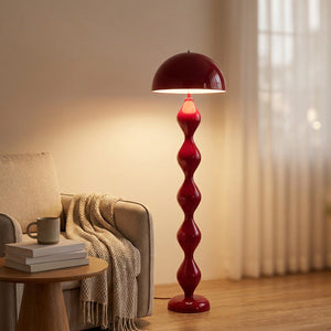 Lampadaire champignon rouge allumé dans un coin lecture avec fauteuil et plaid