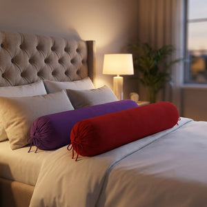 Traversins cylindriques rouge et violet dans une chambre moderne avec lampe de chevet