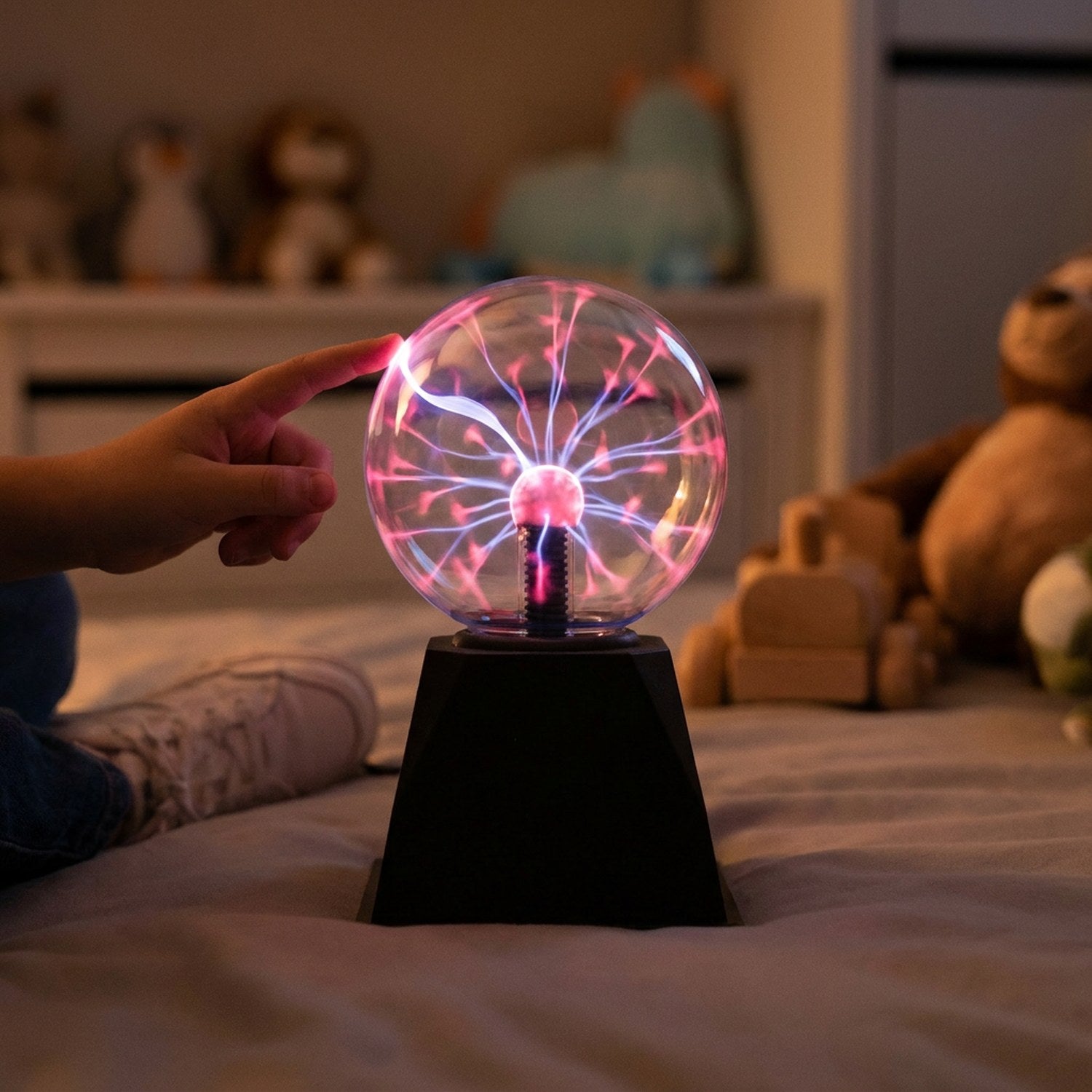 Main d'enfant touchant une lampe boule de plasma allumée dans une chambre