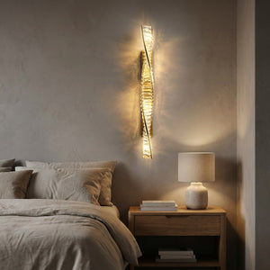 Applique murale dorée en cristal allumée au-dessus d'une table de chevet dans une chambre