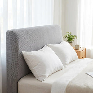 Housse de tête de lit gris clair vue de trois quarts sur un lit avec oreillers blancs