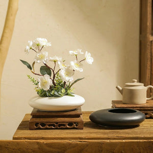 Vase en céramique blanc avec fleurs sur plateau bois